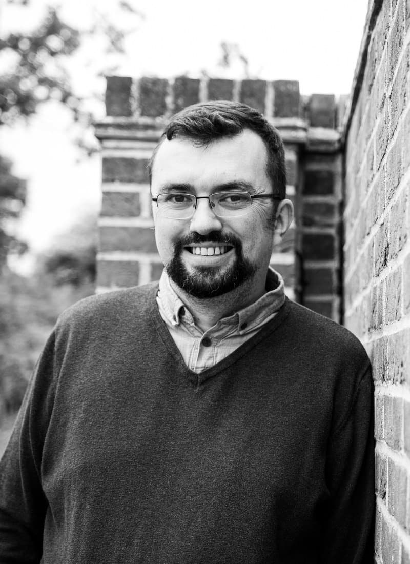 Portrait of Kristian Downer leaning against a brick wall