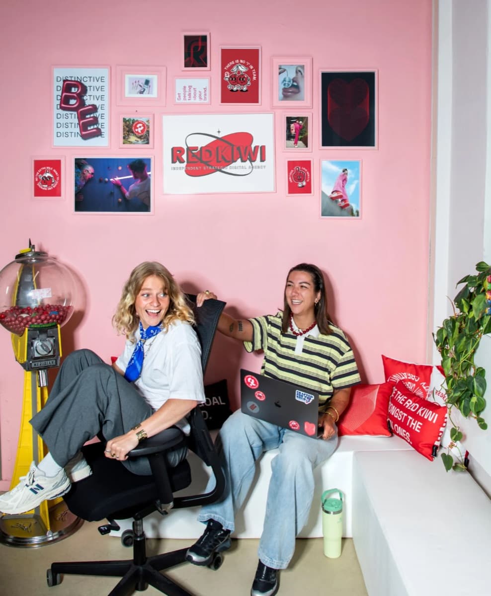 Two Redkiwi team members laughing in the agency’s pink office