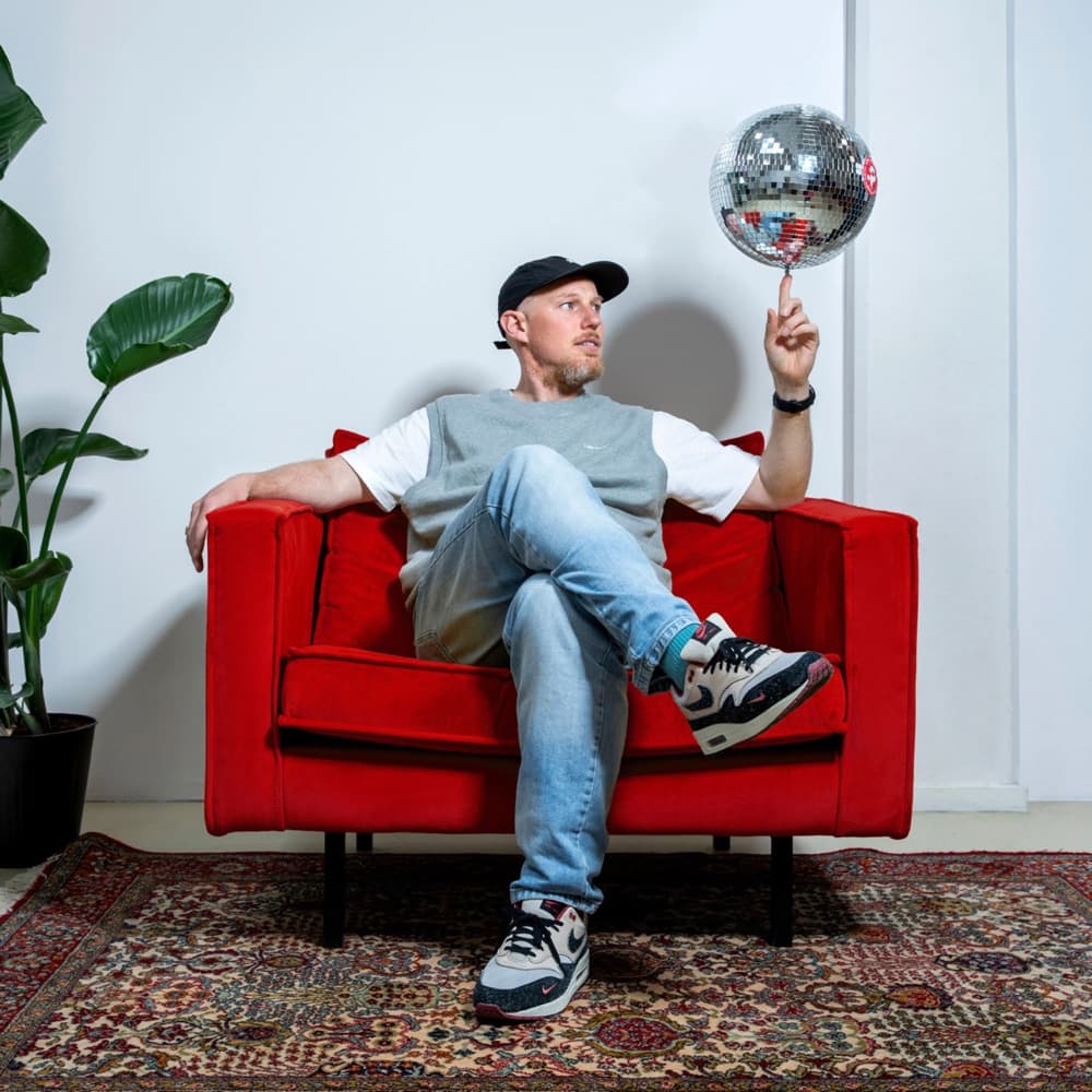 A Redkiwi team member spinning a disco ball while sitting in a red armchair