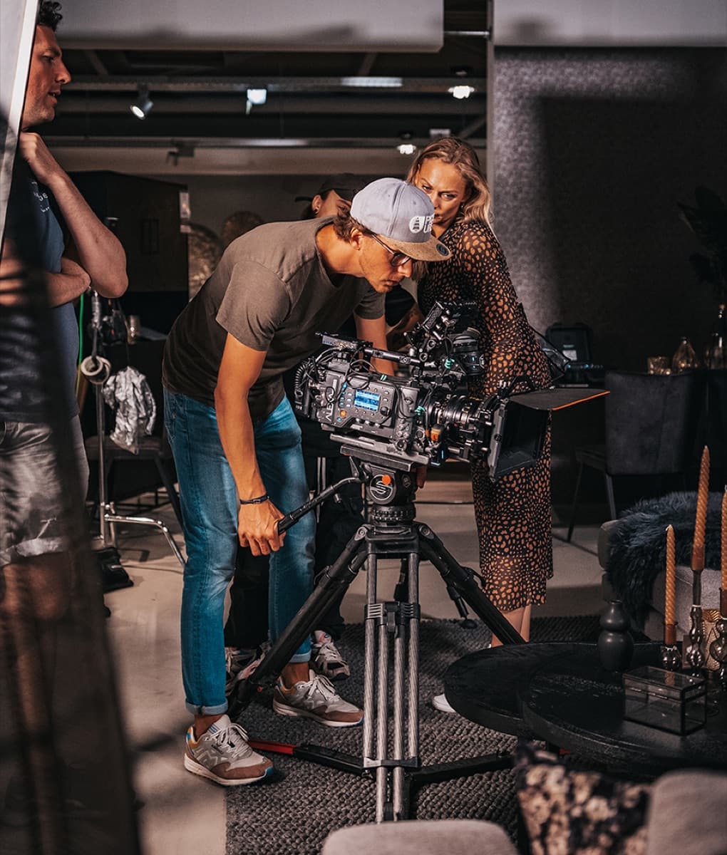A Trenchcoat camera operator filming on set
