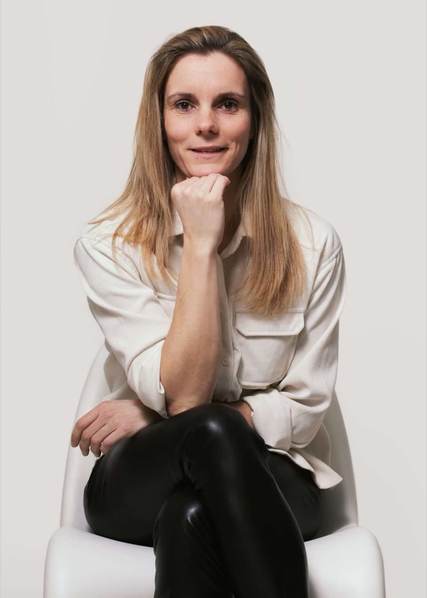 Wendy van Gilst seated on a white chair, resting her chin on her hand